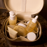 Anare Complete Glow skincare bundle products in a brown beige travel case on a textured surface