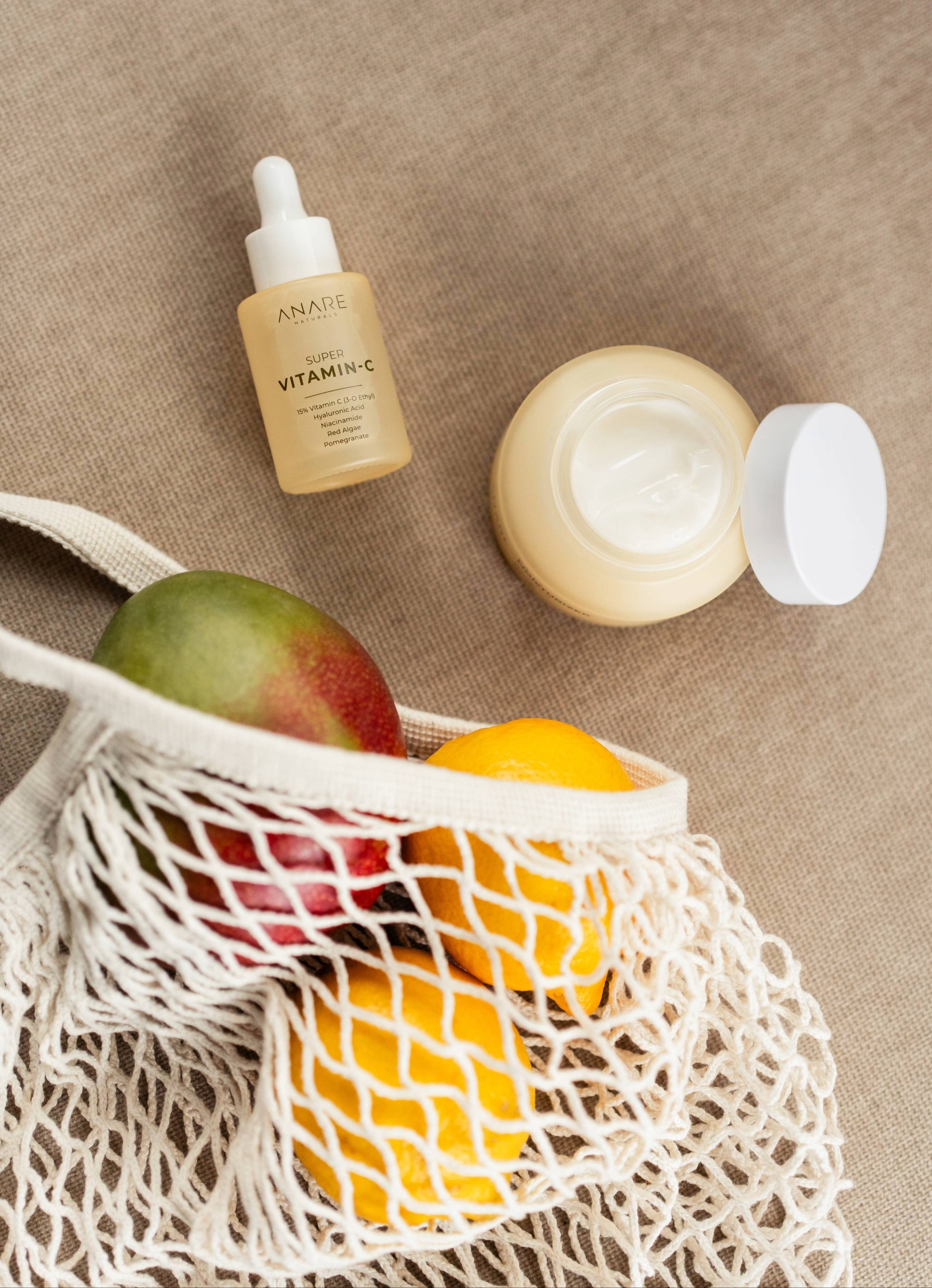 Hydrate & Glow bundle with Super Vitamin C Serum and Daily Moisturizer placed alongside mangos and lemons, emphasizing natural ingredients, vitamins, and daily self-care essentials.