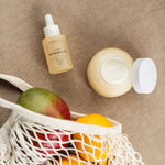 Hydrate & Glow bundle with Super Vitamin C Serum and Daily Moisturizer placed alongside mangos and lemons, emphasizing natural ingredients, vitamins, and daily self-care essentials.