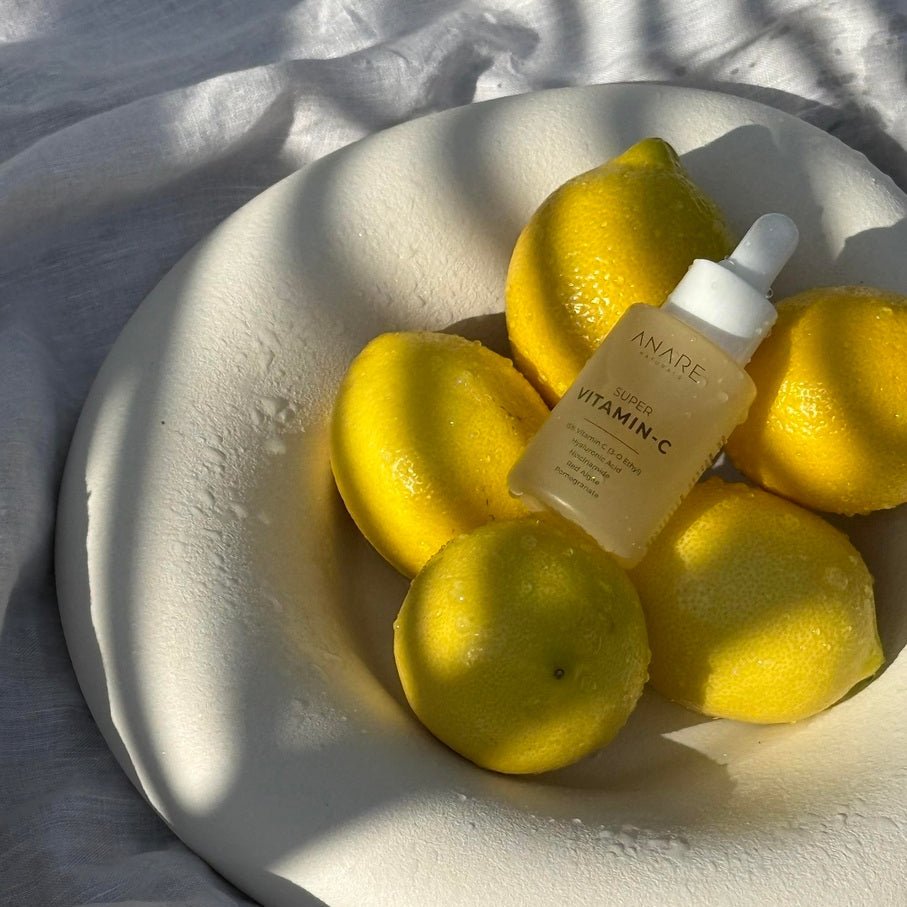 Bowl with lemons and a bottle of 15% Vitamin C skincare product on a textured surface