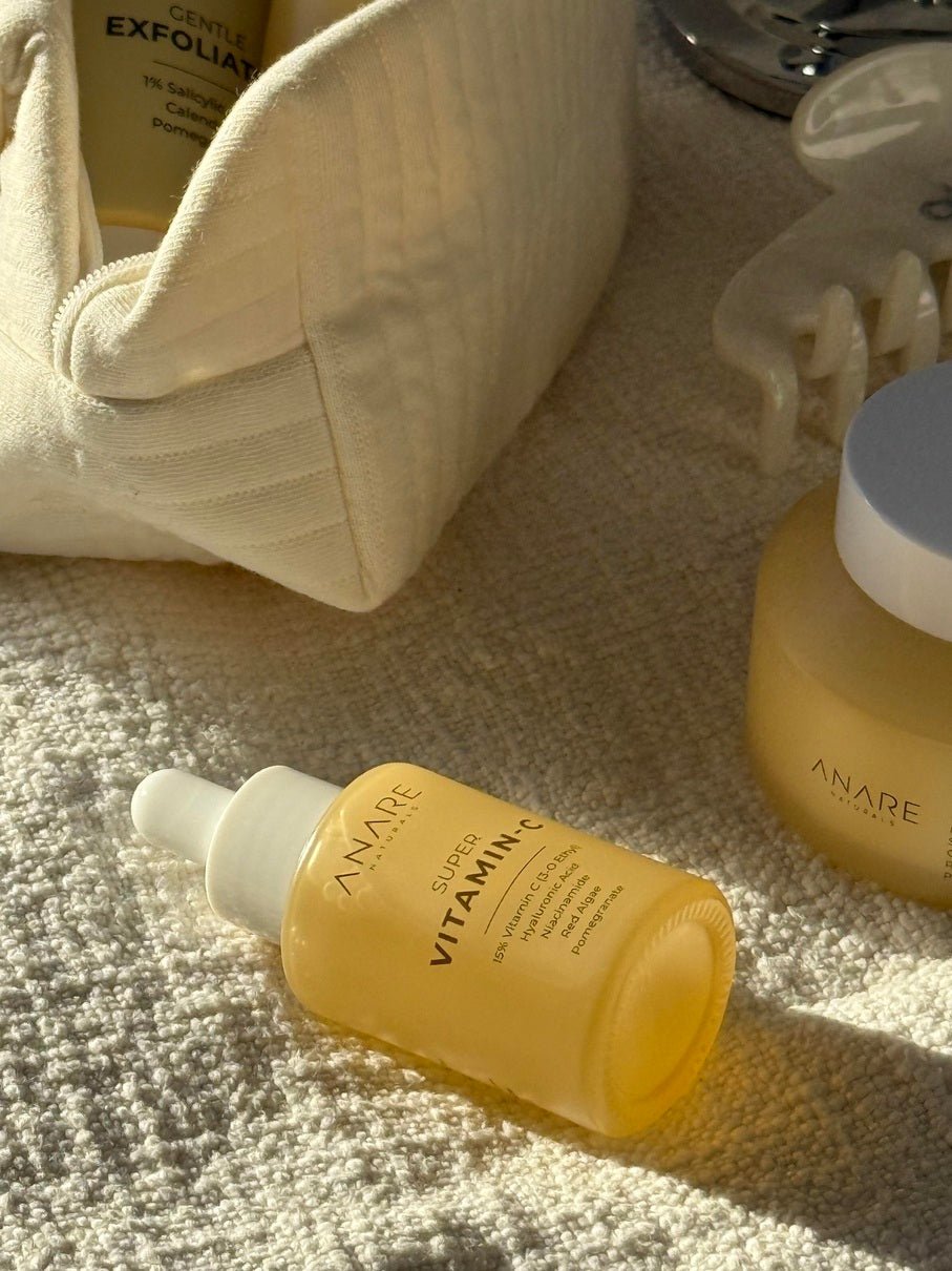 Yellow Vitamin C Serum bottle and other skincare products on light color cloth in sunlight